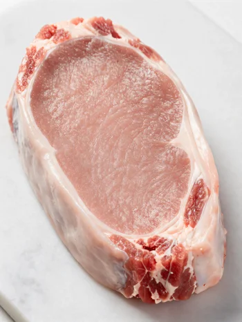 Čerstvé kousky světlého telecího masa s kořením na dřevěném prkénku