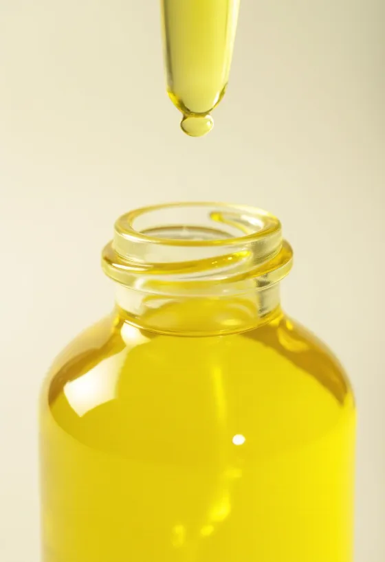 Citronový olej v malé lahvičce vedle čerstvých plátků citronu a kůry