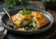 Rozkrojená taštička cornish pasty s kousky ryby a hráškem