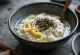Sezamové Congee, krémová rýže podávaná s praženým sezamem a čerstvým zázvorem