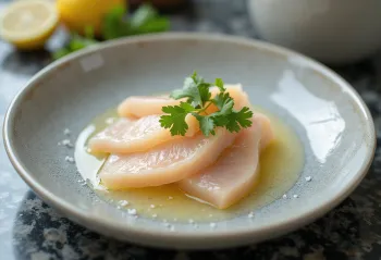 Tiradito s omáčkou yuzu, plátky čerstvé ryby zdobené chilli, koriandrem a limetkou